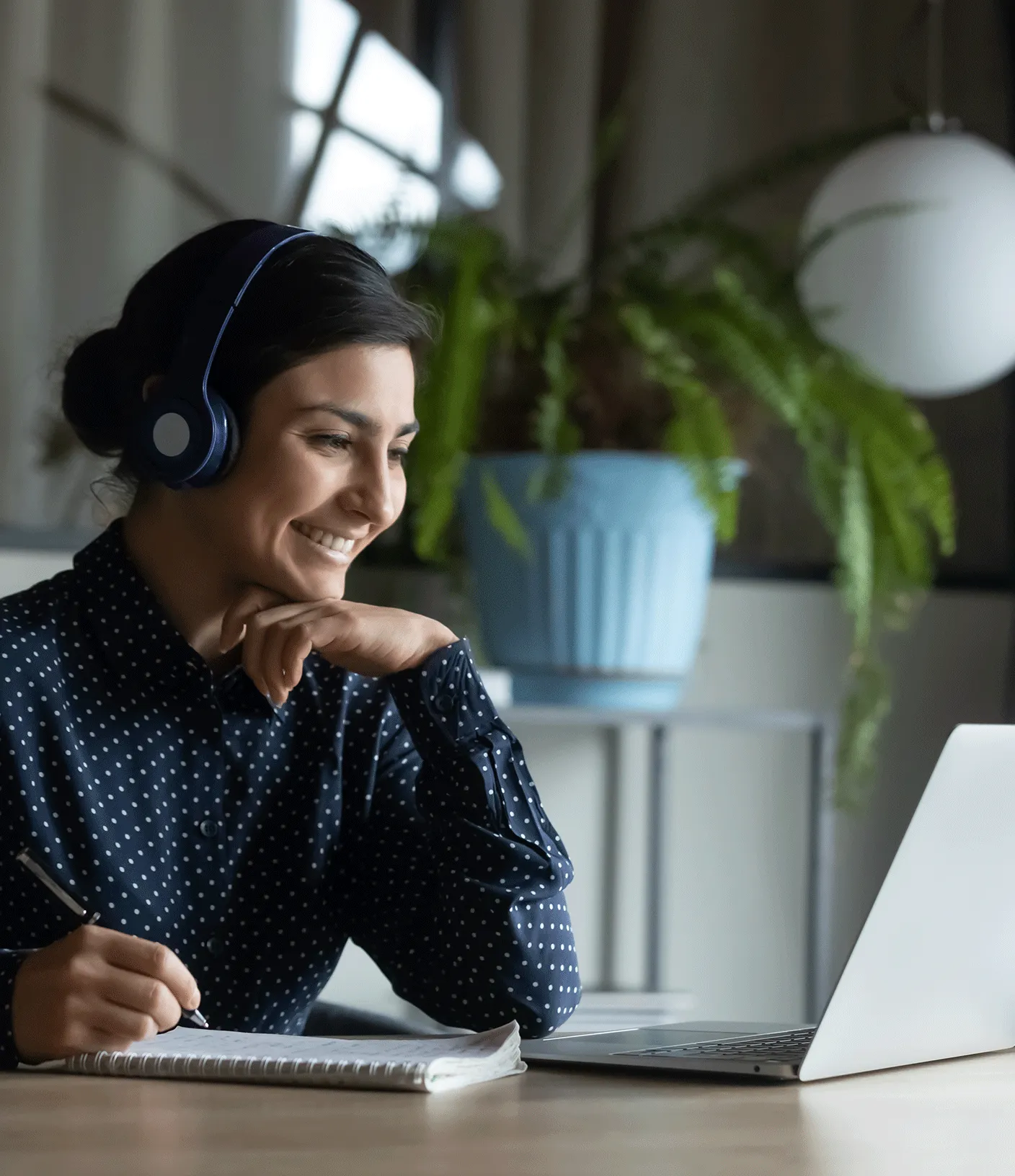 Frau sitzt mit K&ouml;pfh&ouml;hrern vor dem Laptop und schrieibt mit